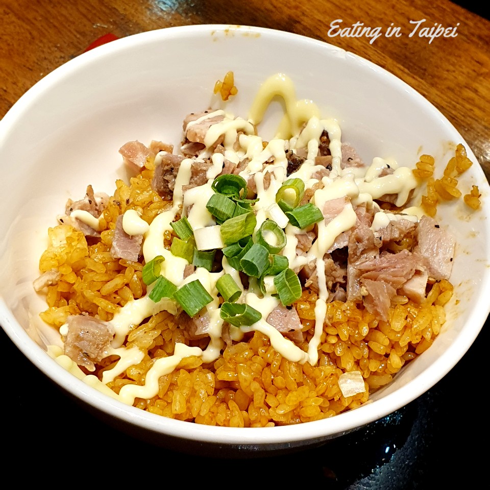 The char su bowl is a bowl of rice topped with small cubes of char su pork, lashed with mayonnaise, and sprinkled with green onions.